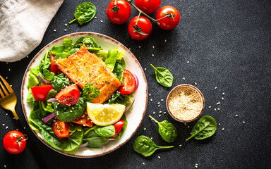 Green salad with vegetables and salmon fillet. Healthy lunch, diet nutrition. Top view on black.