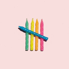 Colorful birthday candles on pastel light pink background. Symbolic party concept. Minimalistic celebration composition.
