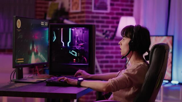 Caucasian gamer girl relaxing playing fast paced space shooter simulation on professional pc setup while talking using gaming headset. Woman streaming on internet rpg action game tournament gameplay.