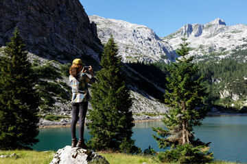 Woman Hiker Standing on a Rock To Take a Photograph of Beautiful Mountains and Lake Environment