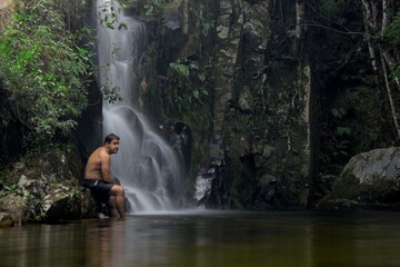 Fototapeta na wymiar A man stand in front a dreamy waterfall in Minas Gerais state, Brazil, during a long expostion shot