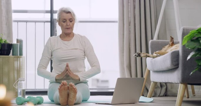 Woman watching yoga class on laptop, following practice and stretching in home zen lesson. Mature yogi sitting on living room floor, finding inner mental health balance or peace in holistic exercise
