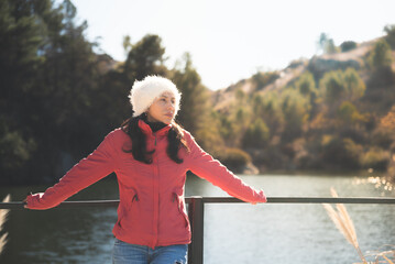 woman with hat, in front of the lake on a sunny autumn afternoon