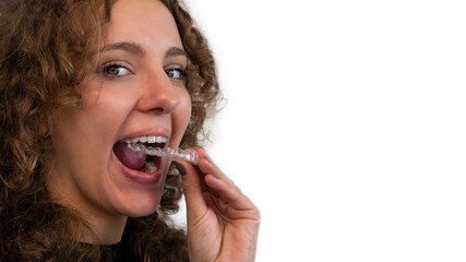 Smiling woman putting on her invisible silicone aligner for dental correction.