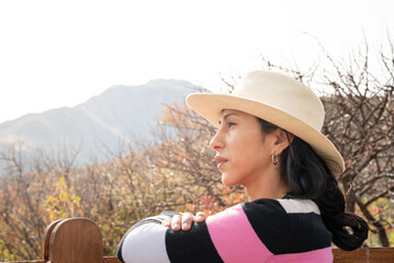 mujer sola con sombrero reposando en tranquera de madera