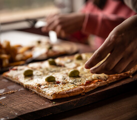 pizza crijiente con muzzarella, salsa de tomates, oregano y aceitunas junto a plato de papas fritas