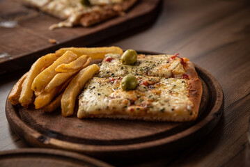 pizza crijiente con muzzarella, salsa de tomates, oregano y aceitunas junto a plato de papas fritas