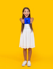 amazed teen child hold present box on yellow background