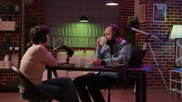 Online radio station host interviewing guest in late night talkshow recording podcast using professional microphone and audio mixer. Man having casual converastion with woman in internet broadcast.