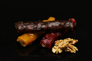 Pieces of churchkhela of different colors and peeled walnuts around the edges in a dark room. Shallow depth of field