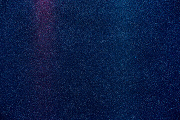 Dark blue fine grained background with vertical beams of red and blue light