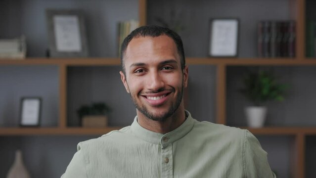 Close up business portrait of confident handsome mixed race man looking at camera and smiling. Young modern male leader, entrepreneur, manager indoors at workplace in office. Successful businessman.