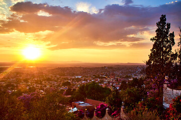 sunset in city with sun in the horizont with yellow colors and purpple clouds and sunshines in san miguel de allende guanajuato 