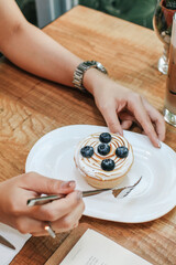 Hand pick up Lemon meringue and blueberry tart in white plate on wooden table. Pie Dessert. Horizontal Copy space