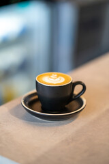 cup of coffee on a table in front of backlit refrigerator
