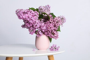 Beautiful lilac flowers in vase on white table