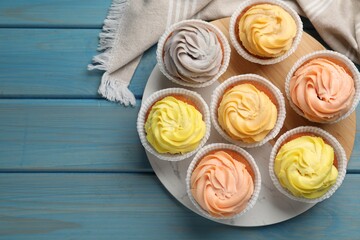 Stand with tasty cupcakes on light blue wooden table, flat lay. Space for text