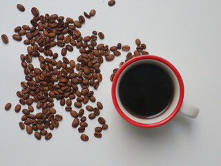 Top view of coffee in red color cup with coffee beans on white background. Flat lay style.