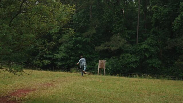 Slow motion of modern sport of axe throwing involves a competitor throwing an axe at a target