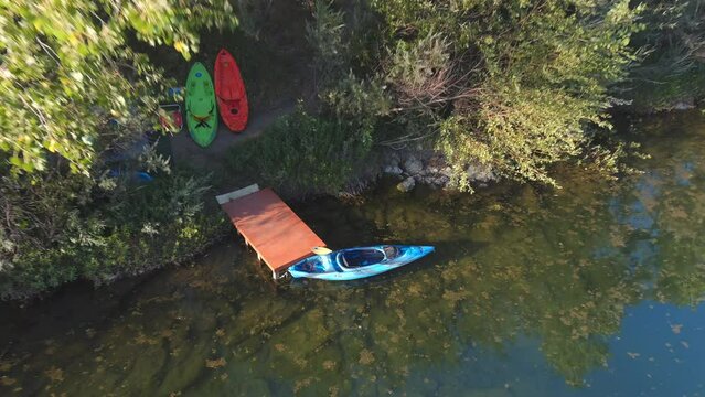 A kayak on a small wooden dock on the Russian River in Central California - pull back ascending aerial view