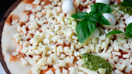 Store bought, uncooked mozzarella and pesto flavored pizza. This oven ready family sized pizza is also covered in cheese, basil and tomato sauce. Italian pizza and fast food concept.