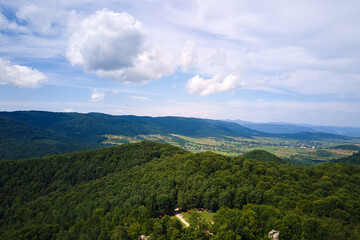 Aerial view of high hills with dark pine forest trees at autumn bright day. Amazing scenery of wild mountain woodland