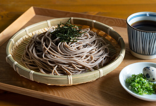 Zaru-soba and condiments on a wooden table.