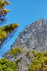 Beautiful view of a mountain and a blue sky with green nature and copy space from below. Scenic and quiet mountaintop or summit with a rocky landscape view of a remote location on a sunny summer day