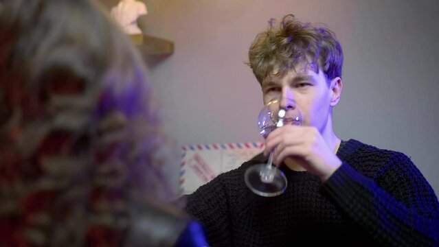 A young couple meets in a nightclub bar. The guy winces from alcohol. The couple drinks alcohol. Night club