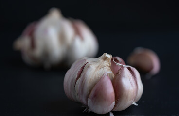 cabezas de ajo, con gajos sueltos sobre fondo negro