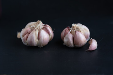 cabezas de ajo, con gajos sueltos sobre fondo negro
