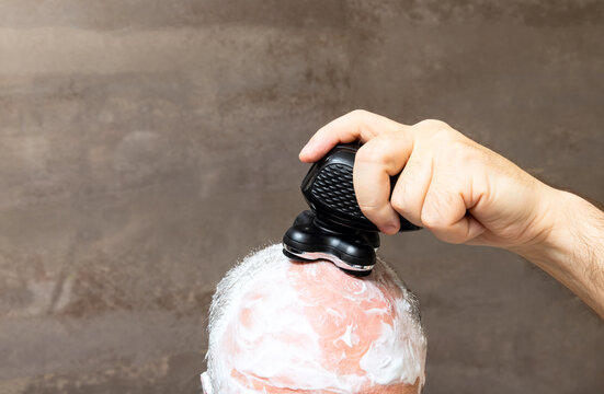 Balding man shaving his head with foam and trimmer