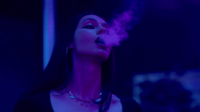 Close-up of a girl in a club, dancing and smoking an electronic cigarette. Night club