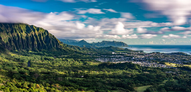 Panoramic aerial image from the Pali Lookout on the island of Oahu in Hawaii. With a bright green rainforest, vertical cliffs and vivid blue skies.