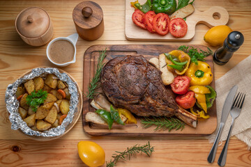 Barbecue Tomahawk Steak on wooden plate.Grilled tomahawk ribeye steak with baked potatoes ,mashroom, roasted sweet peppers and tomato ready to serve. 