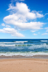 Fototapeta na wymiar Beautiful, calm and quiet view of the beach, ocean and seashore against a cloudy blue sky on a summer day. Peaceful and remote ocean and sea with waves rolling into the shore in a natural environment