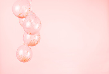 A monochromatic peach pink confetti clear balloons against a light pink backdrop