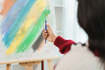 The art concept, Asian female artist measuring proportions with paint brush on canvas for painting
