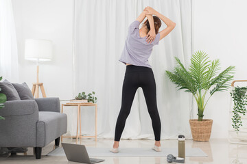 Yoga exercise concept, Young Asian woman stretching arms while doing yoga exercise online at home