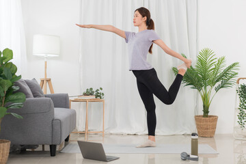 Yoga exercise concept, Young Asian woman stretching leg and arm while doing yoga exercise online