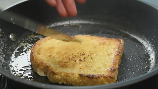 Preparation and turning of French toast in a frying pan.
