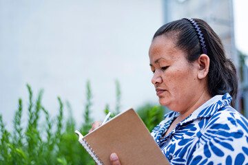 A young Asian woman with black hair sits on a reading chair against a flower garden background.