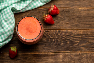 Glass of fresh strawberry milkshake, smoothie and fresh strawberries wooden background.