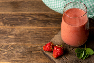 Glass of fresh strawberry milkshake, smoothie and fresh strawberries wooden background.