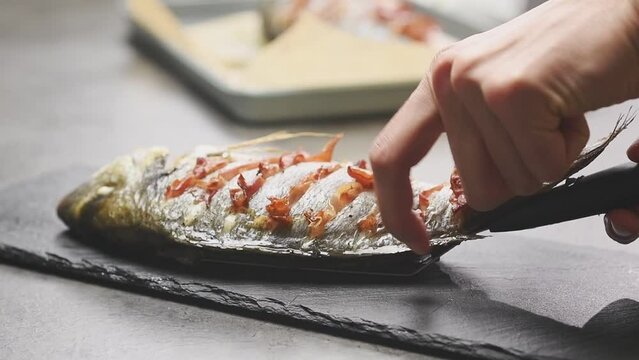 Chef serves oven baked sea bream with prosciutto crudo.
