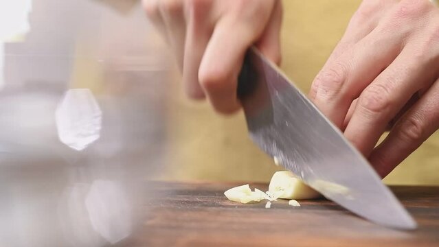 Cutting garlic on a wooden cutting board, slow motion.
