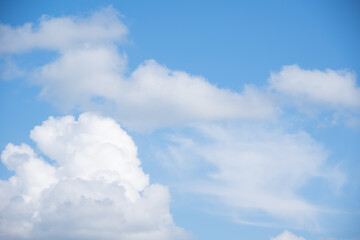 Naklejka na ściany i meble Blue sky background with white fluffy cumulus clouds. Panorama of white fluffy clouds in the blue sky. Beautiful vast blue sky with amazing scattered cumulus clouds.