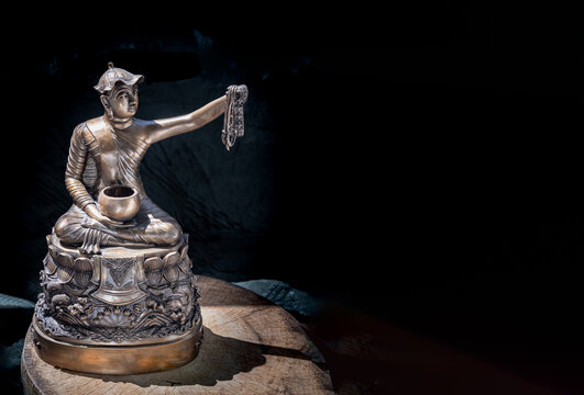 Bronze figurine of Phra upagupta or Phra bua khem statue on dark background with Natural Light. Copy space, Selective focus.