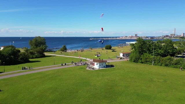 People Playing And Flying Kites On A Windy Day At Sibbarp Park And Campsite In  Limhamn, Sweden. - aerial pullback