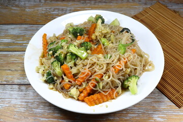 Traditional fried rice noodle mixed with fresh vegetable serving on the plate. Famous street food menu in Asia restaurant. High fiber and low fat recipe.